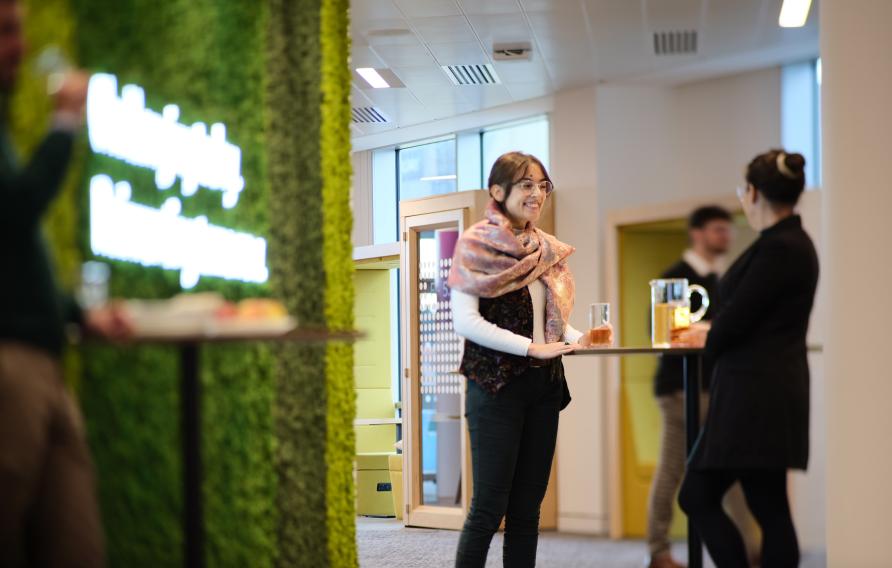 亚洲体育博彩平台 women in an office talking in front of a green moss wall