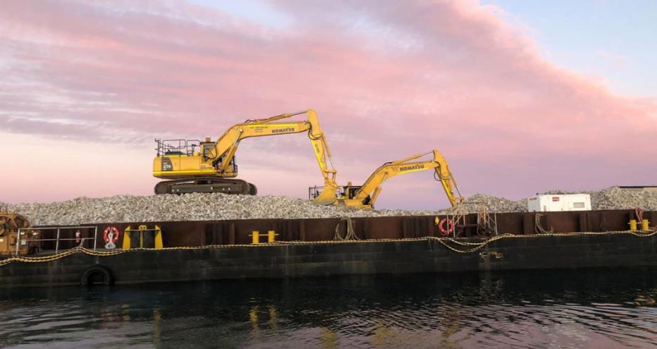 两台在温达拉礁施工的挖掘机，身后是夕阳下粉红色的天空