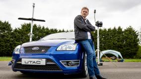 U.K. Secretary of State for Transport Grant Shapps sitting on blue car on test track