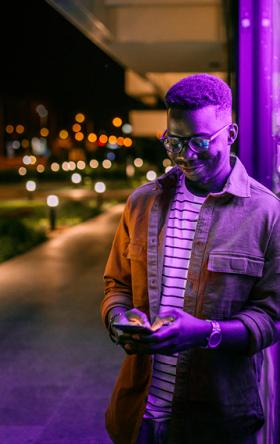 Young Black man in glasses looks down at a cellphone