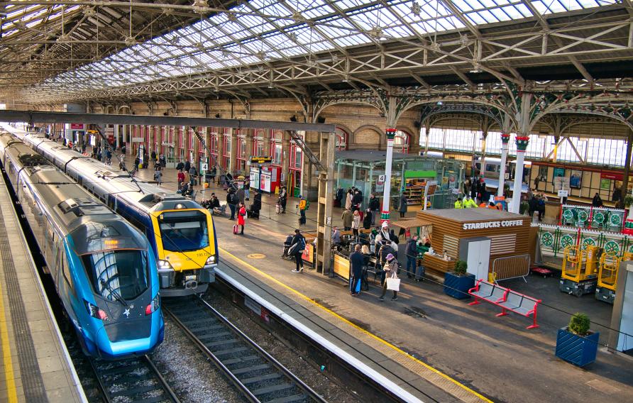 Two trains at platforms in Preston Station in the north west of England in the UK. The architecture of the roof is visible.