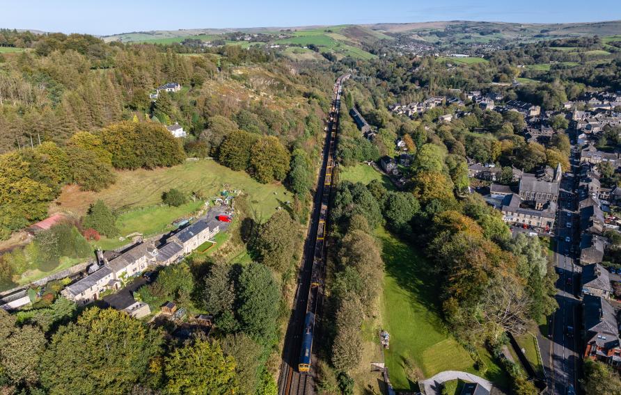 Aerial view of goods train, railway, fields and housing.