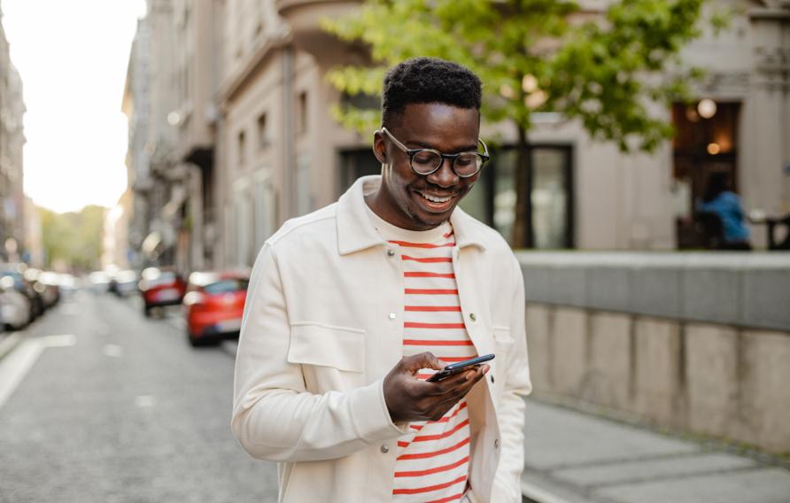  The portrait of an African-American man is on the street, he is walking and using a mobile phone on the go