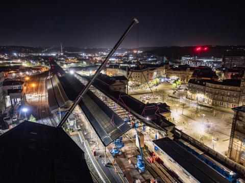 Aerial view at night with work being done on roof canopy of a station platform.