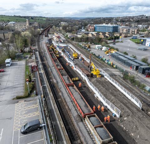 Aerial view of railway track works, workers and diggers.