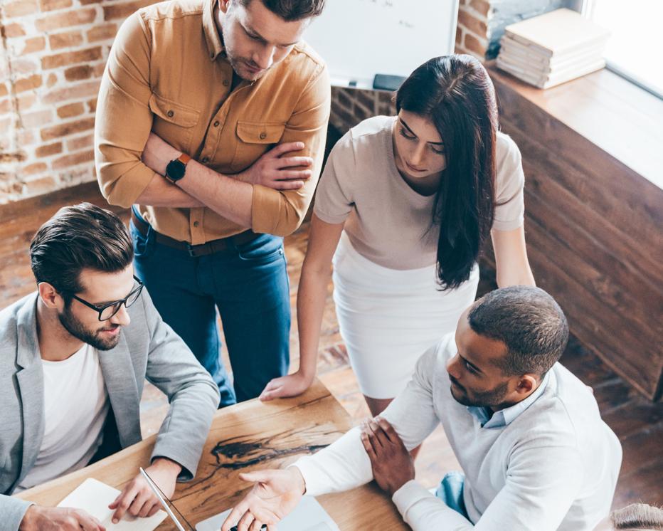 Top view of group of five young people discuss something and gesturing while leaning to the table in office