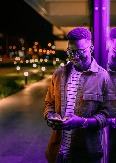 Young Black man in glasses looks down at a cellphone